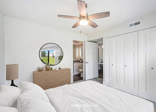 a bedroom with a bed and a ceiling fan leading to a bathroom at The Crossings Apartments, Michigan, 49508