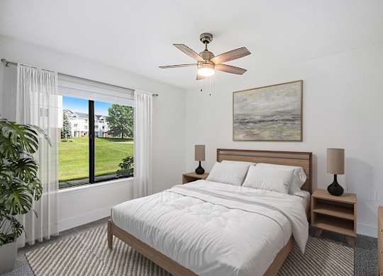 A bedroom with a large bed, a ceiling fan, and a large window at Byron Lakes Apartments, Michigan, 49315