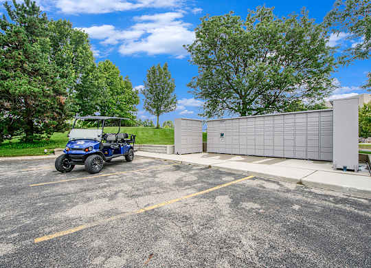 A blue golf cart is parked next to Amazon Hub package lockers at The Crossings Apartments in Grand Rapids, MI