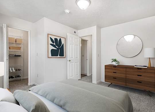 A bedroom with a bed, dresser, mirror and walk in closet at The Highlands Apartments in Elkhart, IN
