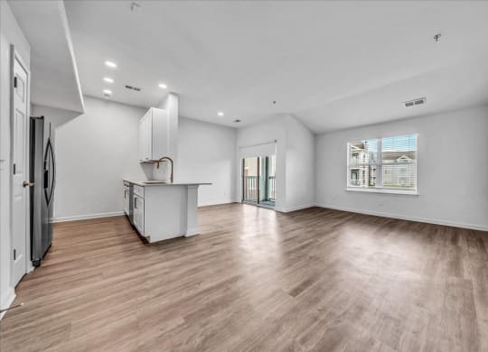 an empty living room with a kitchen and a large window at The Vinings Apartments in Richmond, VA 23234