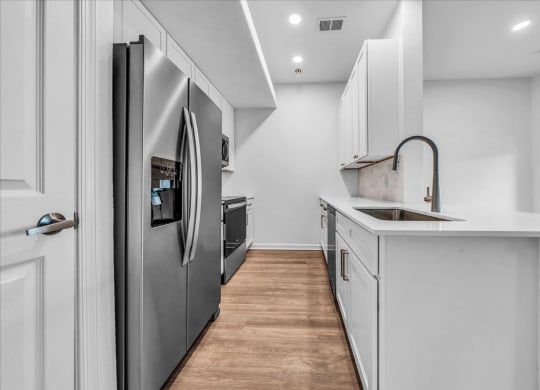 a kitchen with white cabinets and a stainless steel refrigerator at The Vinings Apartments in Richmond, VA 
