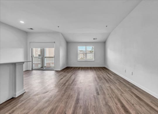 an empty living room with wood flooring and a balcony at The Vinings Apartments in Richmond, VA 23234