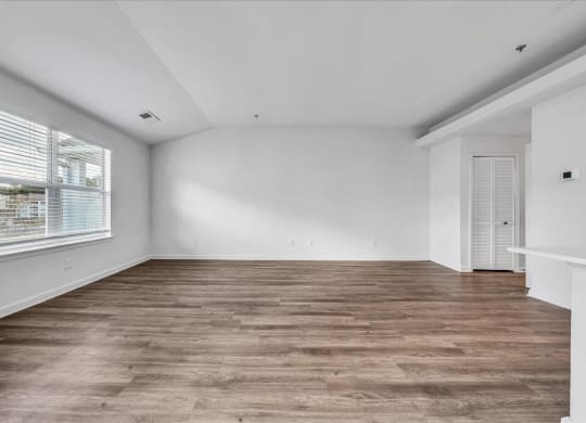 the living room of a home with a large window and wooden floors at The Vinings Apartments in Richmond, VA 
