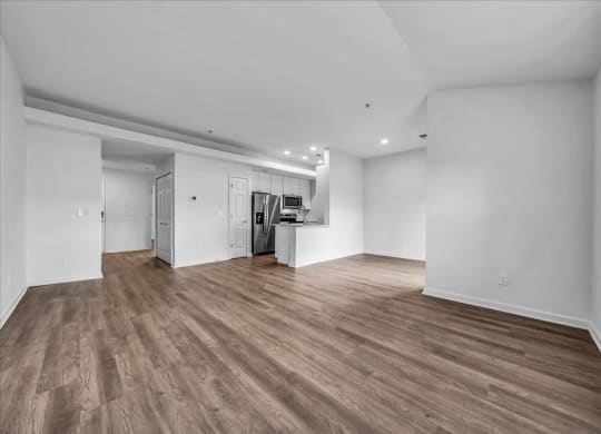 the living room and kitchen of a new home with white walls and wood floors at The Vinings Apartments in Richmond, VA 