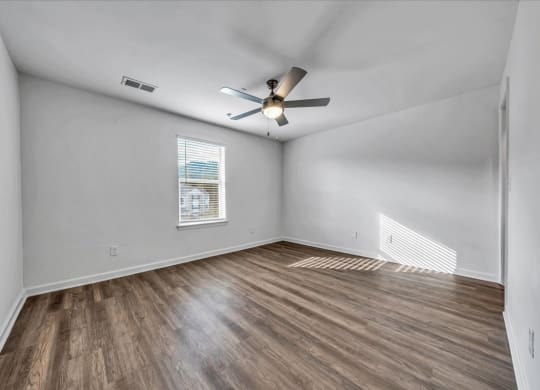 an empty living room with a ceiling fan and a window at The Vinings Apartments in Richmond, VA 