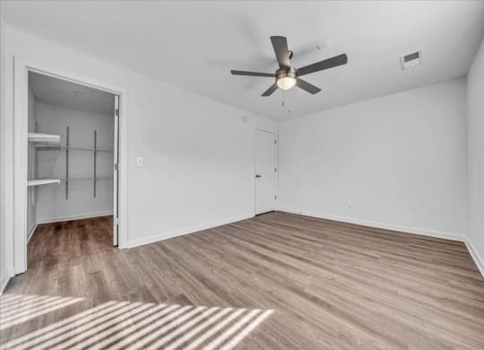 an empty living room with a ceiling fan and a closet at The Vinings Apartments in Richmond, VA 