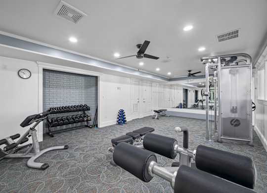 A gym with a variety of equipment including weights and a bench pressk at Timberlane Apartments, Peoria, Illinois