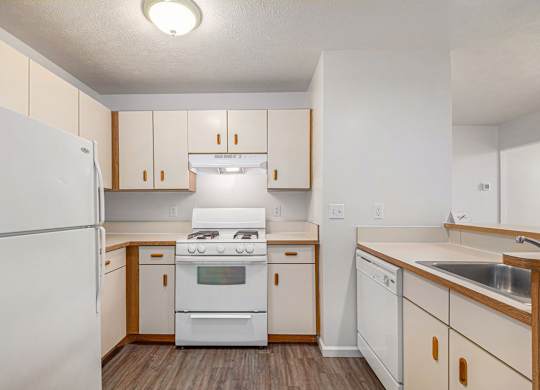 A kitchen with white appliances and wooden cabinets at Tracy Creek Apartments, Ohio
