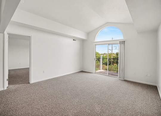 A large empty living room with a cathedral ceiling and a large arched window at Tracy Creek Apartments, Ohio
