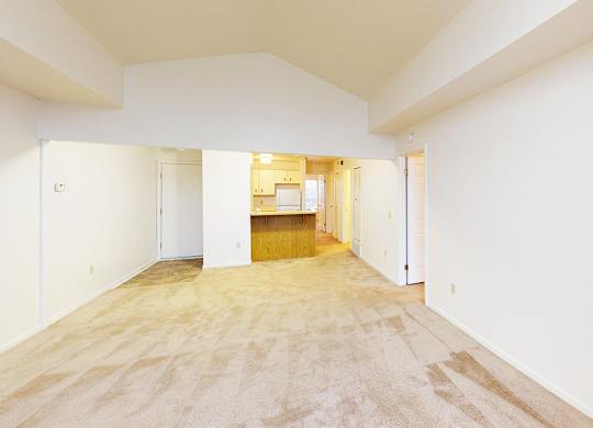 A spacious living room with a cathedral ceiling and plush carpet at Tracy Creek Apartment Homes in Perrysburg, OH