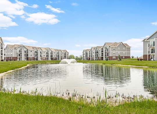 A scenic pond with a fountain behind apartments at Tracy Creek Apartments, Perrysburg
