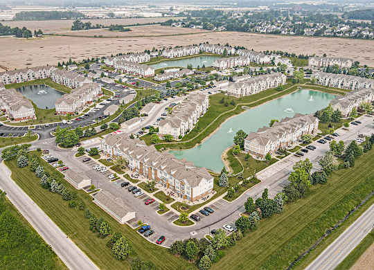A bird's eye view of a residential area with a pond and apartment buildings at Tracy Creek Apartments, Perrysburg