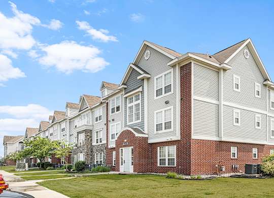 An exterior apartment building with a clear blue sky above at Tracy Creek Apartments, Perrysburg