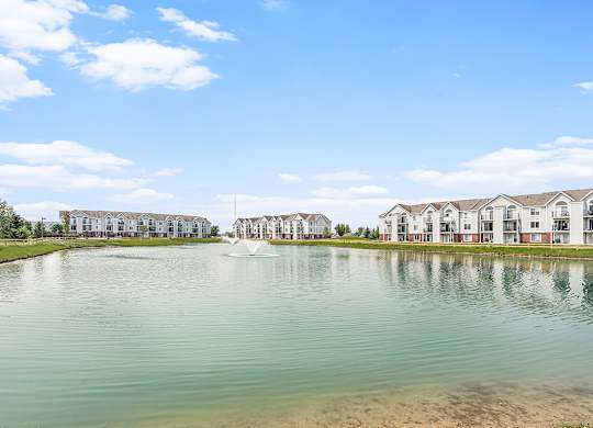 A large body of water with a fountain in the middle and apartment buildings in the background at Tracy Creek Apartments, Perrysburg