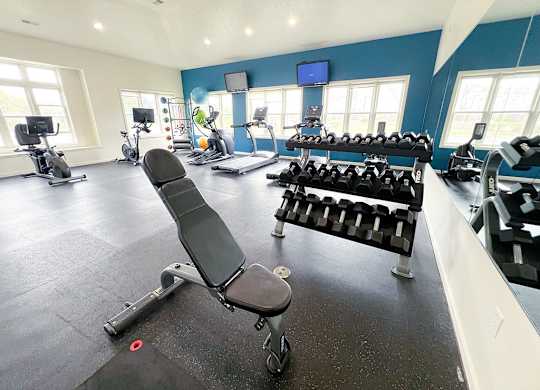 A gym with a variety of equipment including weights and cardio machines at Tracy Creek Apartments, Perrysburg, OH, 43551