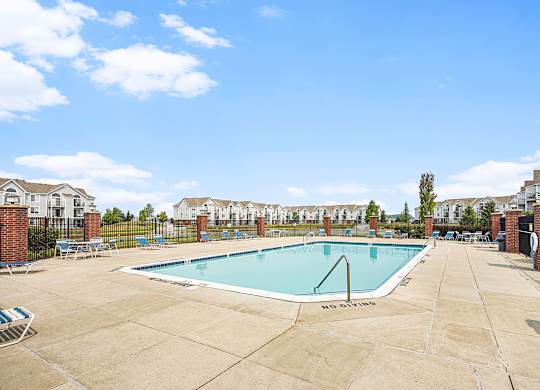 A large swimming pool with Wi-Fi surrounded by a concrete patio and a fence at Tracy Creek Apartments, Perrysburg