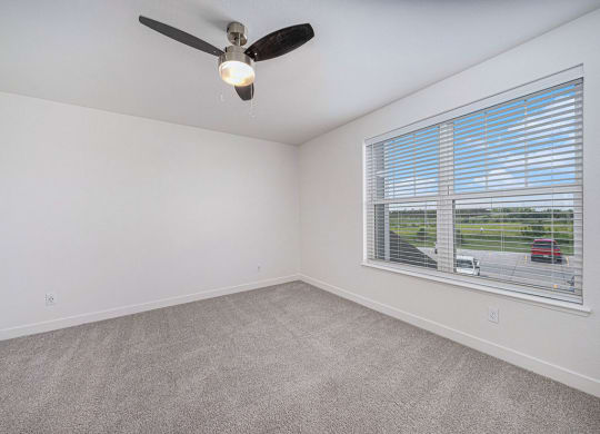 bedroom with a large window and a ceiling fan at Trade Winds Apartment Homes, Elkhorn, Nebraska