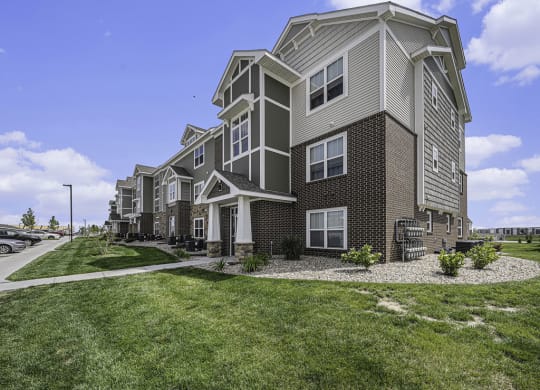 apartment building with grass and sidewalks at Trade Winds Apartment Homes in Elkhorn, NE 68022