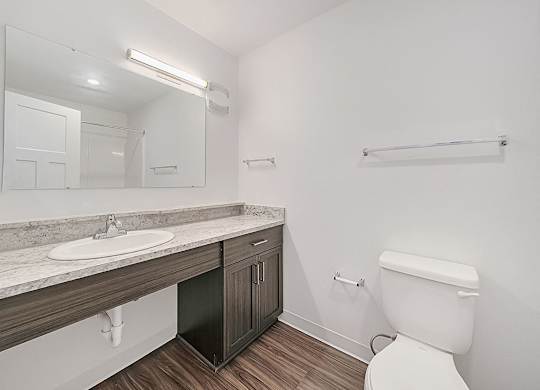 A white toilet sits in a bathroom next to a sink and mirror.