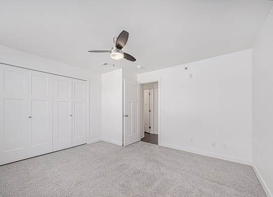 A room with a ceiling fan and carpeted floor.