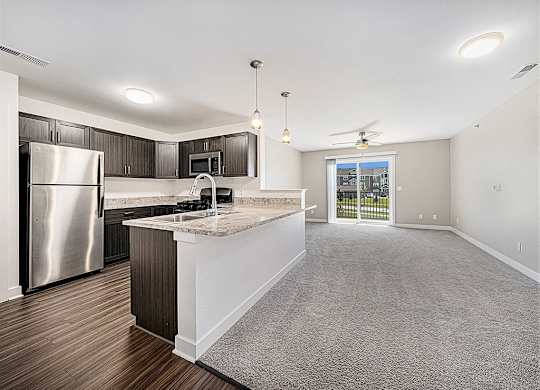 A kitchen with a refrigerator, microwave, and a countertop with a sink.