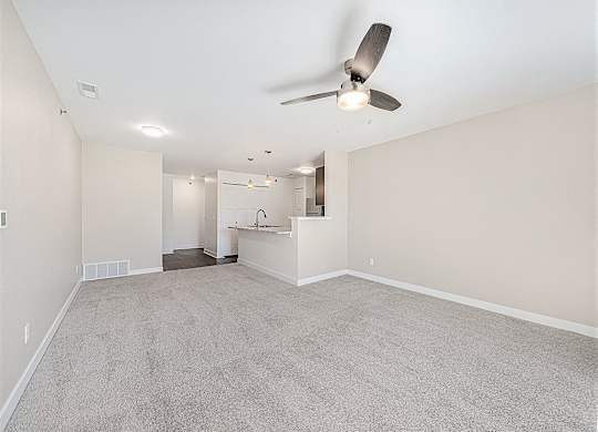 A room with a ceiling fan and carpeted floor.