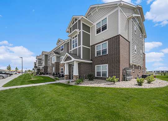 apartment building with grass and sidewalks at Trade Winds Apartment Homes in Elkhorn, NE 68022