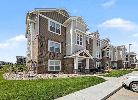 A modern apartment building with a car parked in front at Trade Winds Apartment Homes, Elkhorn, NE, 68022