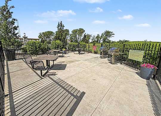 A sunny day at the outdoor grilling and seating area with tables and chairs at Trade Winds Apartment Homes in Elkhorn, NE