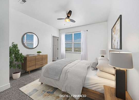 A bedroom with a bed, a ceiling fan, and a window with blinds at Trade Winds Apartment Homes, Elkhorn, Nebraska
