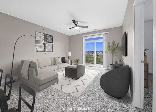 A modern living room with a grey sofa, a black chair, and a 9 foot ceiling at Trade Winds Apartment Homes, Elkhorn, Nebraska