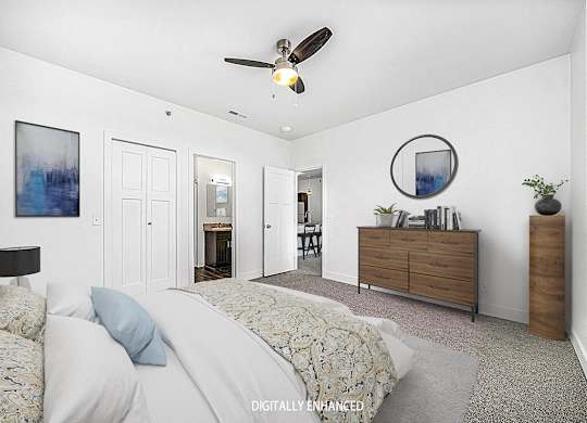 A bedroom with an ensuite, a bed, dresser, and ceiling fan at Trade Winds Apartment Homes, Elkhorn, Nebraska