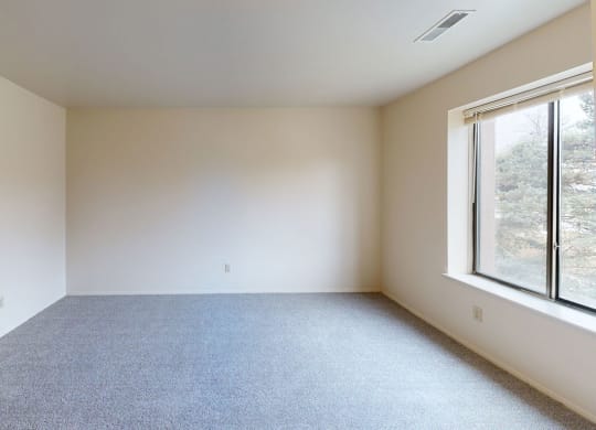 spacious bedroom with a large window and carpet  at Trappers Cove Apartments, Lansing