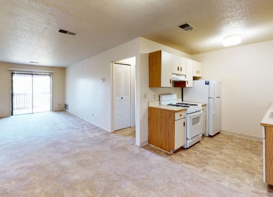 galley style kitchen and living room with a slider to a balcony at Trappers Cove Apartments, Michigan, 48910