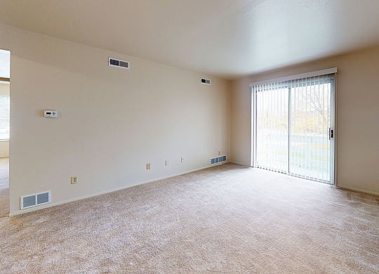 living room with a sliding glass door to private patio  at Trappers Cove Apartments, Lansing, 48910