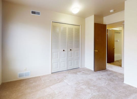 bedroom with a closet and a large window  at Trappers Cove Apartments, Lansing