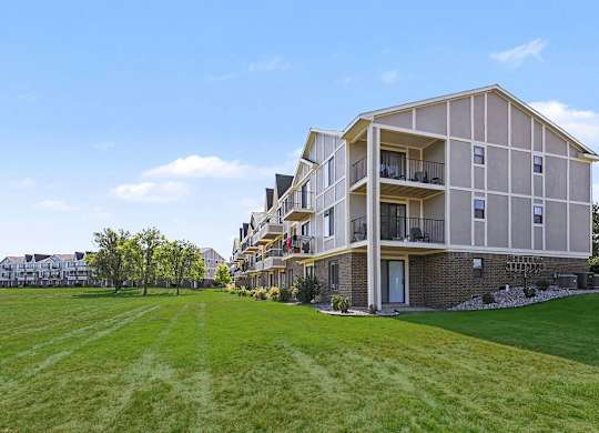 A large apartment building with park-like grounds at Trappers Cove Apartments, Lansing, 48910