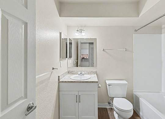 An upgraded bathroom with a toilet, sink, and bathtub at Trappers Cove Apartments, Lansing
