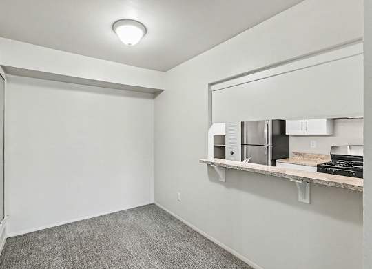 A dining room with a grey carpet and a breakfast bar at Trappers Cove Apartments, Lansing