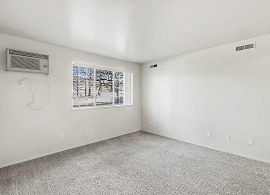A garden style living room with a window showing trees outside at Trappers Cove Apartments, Lansing