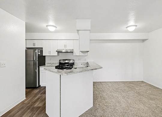 A kitchen with white cabinets and a breakfast bar at Trappers Cove Apartments, Lansing