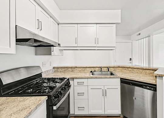 A kitchen with stainless steel appliances and white shaker-style cabinets at Trappers Cove Apartments, Lansing