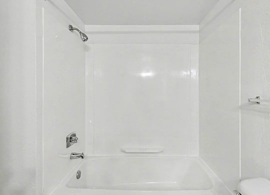 A white bathroom with a bathtub and toilet at Trappers Cove Apartments, Lansing