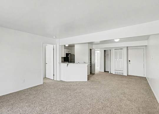 A spacious living room with carpeting and a breakfast bar at Trappers Cove Apartments, Lansing