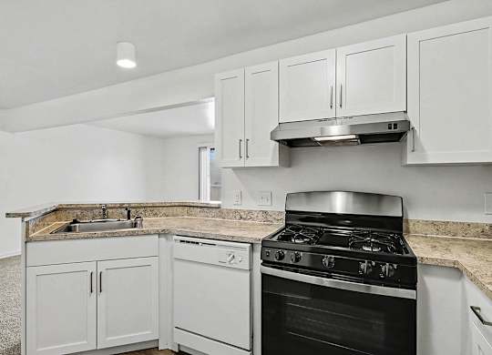 An upgraded kitchen with a dishwasher and white cabinets at Trappers Cove Apartments, Lansing