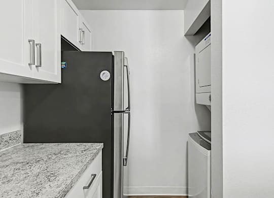 A stainless steel refrigerator in a kitchen with a washer and dryer at Trappers Cove Apartments, Lansing