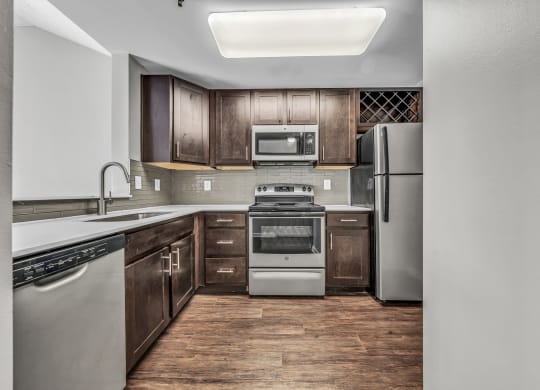 an empty kitchen with stainless steel appliances and wooden cabinets at Trophy Club at Bellgrade, Midlothian, VA, 23113
