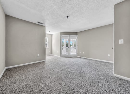 an empty living room with gray walls and a door to a balcony at Trophy Club at Bellgrade, Midlothian, VA, 23113