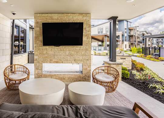 Modern outdoor seating area with a flat screen TV mounted on a stone wall at Upper Vue Flats, Dublin, Ohio